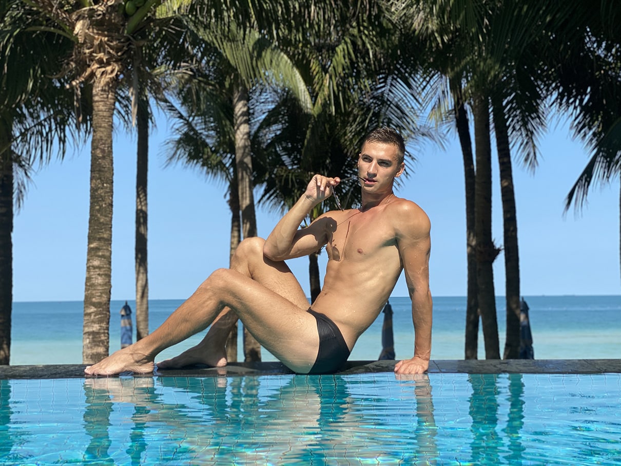 Male model by tropical pool with palms